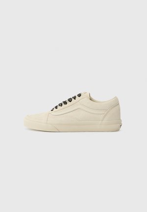 Beige semskinn sneakers med lav toppdesign, svart snøring, gummisåle og stripete detalj på siden. Glatt tekstur med minimale aksenter.