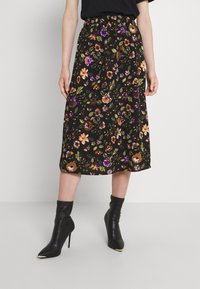 Black floral skirt with a relaxed fit, featuring colorful flower patterns, an elastic waistband, and a mid-length hem. Paired with black heeled boots.
