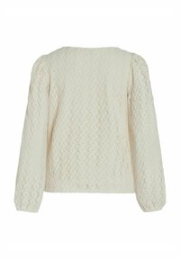Blouse à manches longues couleur crème avec motif zigzag texturé et épaules bouffantes, vue de dos.