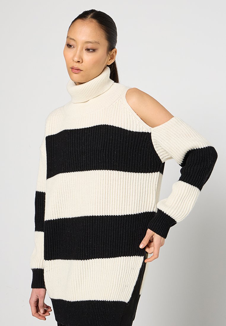 Chunky gebreide trui in zwart en crème strepen, met een hoge col en een cold-shoulder ontwerp. Geribbelde textuur, relaxte pasvorm.