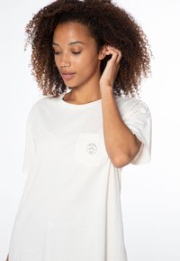 Lichtbeige katoenen t-shirt met een ronde hals, korte mouwen en een borstzak met een cirkelvormige logoafdruk.