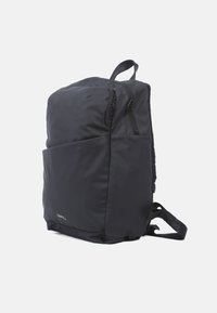 Svart nylonryggsäck med flera dragkedjefack, vadderade axelremmar och en strömlinjeformad design. Har ett framfack för enkel åtkomst.
