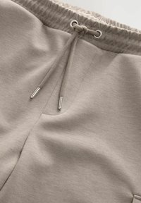 Pantalon de survêtement en mélange de coton gris clair avec une taille élastique, une fermeture à cordon de serrage et une poche latérale au toucher lisse.