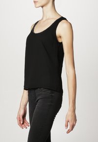 Débardeur noir sans manches avec un col rond, orné d'une fine bordure en dentelle sur le bord. Texture lisse ; coupe décontractée, longueur à la hauteur des hanches.