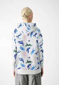 Hooded sweatshirt with a white base, featuring a colorful pattern of abstract human figures in blue, green, pink, and black.