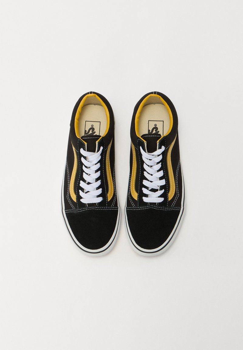 Sneaker in suede nero con dettagli gialli, lacci bianchi e una spessa suola in gomma bianca. Presenta cuciture a contrasto e un collare imbottito.