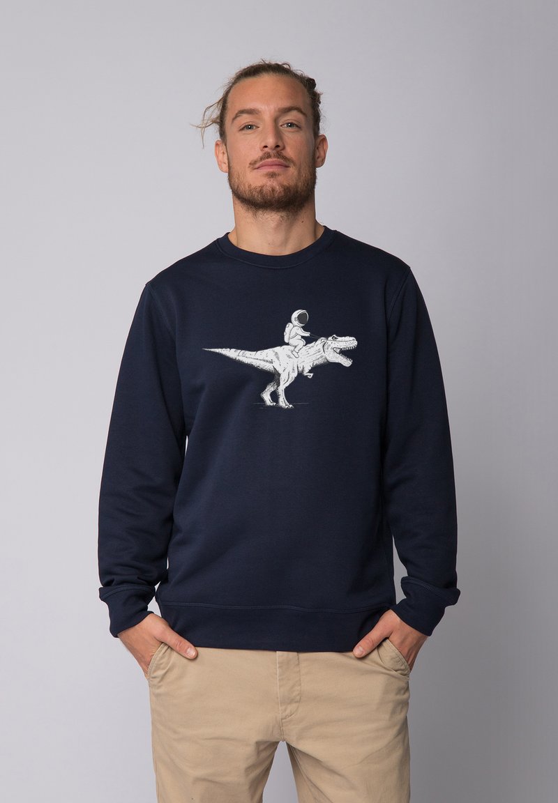 Sweatshirt bleu marine en coton, présentant une illustration blanche d'un astronaute chevauchant un dinosaure sur le devant. Col rond et poignets côtelés.