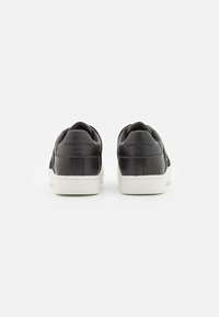Zwarte leren sneakers met een witte rubberen zool, met een gladde textuur en branding op de hiel. Minimalistisch ontwerp zonder extra accenten.