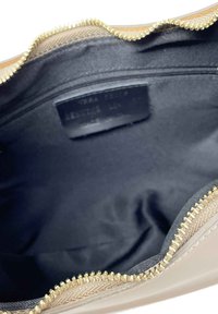 Růžová a béžová taška na zip s vlnitým okrajem, s hladkým koženým vnějším povrchem a černým textilním interiérem s kapsou na zip.