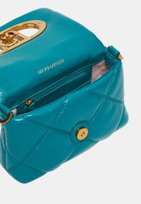 Bolsos de piel color agua con textura acolchada, herrajes en tono dorado y un cierre circular. El interior cuenta con un pequeño bolsillo con cremallera.