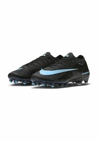 Par de botas de fútbol Nike negras con logo Swoosh azul claro y tacos, diseñadas para superficies de terreno firme, mostradas una al lado de la otra.