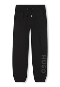 Zwarte joggingbroek van zacht materiaal, met zijzakken, een trekkoord in de tailleband, en "HUGO" in grijs gedrukt langs het linkerpoot.