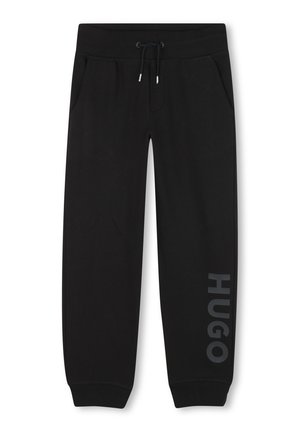 Zwarte joggingbroek van zacht materiaal, met zijzakken, een trekkoord in de tailleband, en "HUGO" in grijs gedrukt langs het linkerpoot.