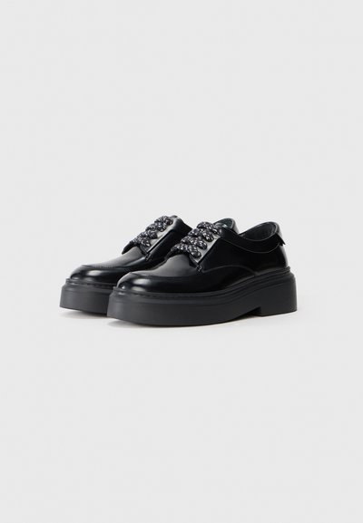 Scarpe in pelle nera con suola in gomma spessa e lacci intrecciati. Presentano una finitura liscia e un design con punta arrotondata.