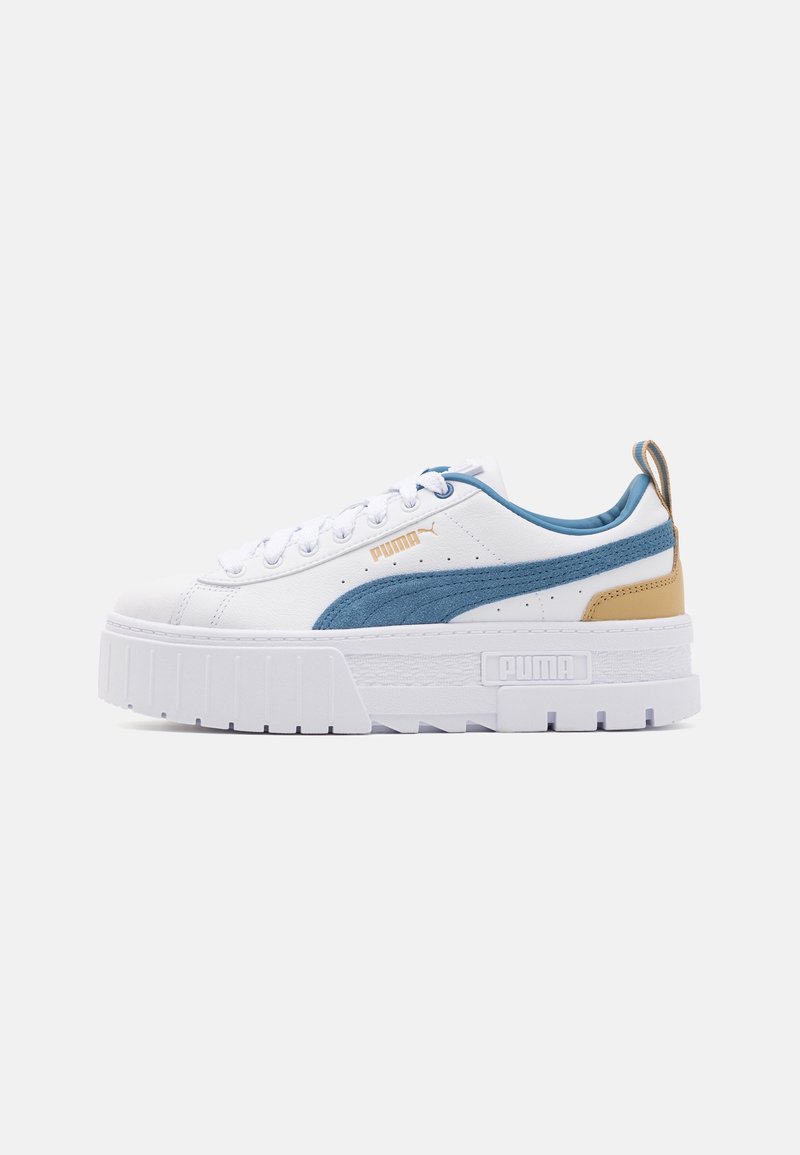 Baskets à plateforme blanches Puma avec bande en daim bleu, détail beige au talon, lacets blancs et semelle épaisse texturée sur fond uni.