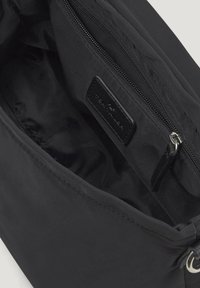 Bolso de tela negro abierto para mostrar el interior con un bolsillo con cremallera y una etiqueta de marca de cuero en el interior.