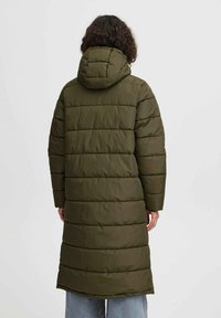Manteau rembourré vert olive, de longueur genoux avec capuche ; présente un design matelassé avec des coutures horizontales et des manches longues. Style minimaliste.