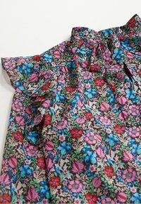 Blomstret blouse i en mørk stof, udsmykket med intrikate mønstre af pink, røde og blå blomster; rynkede ærmer og krave detaljer.