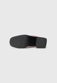 Black shoe sole with a textured tread pattern and a block heel. Upper made of a glossy red material with a sleek design.