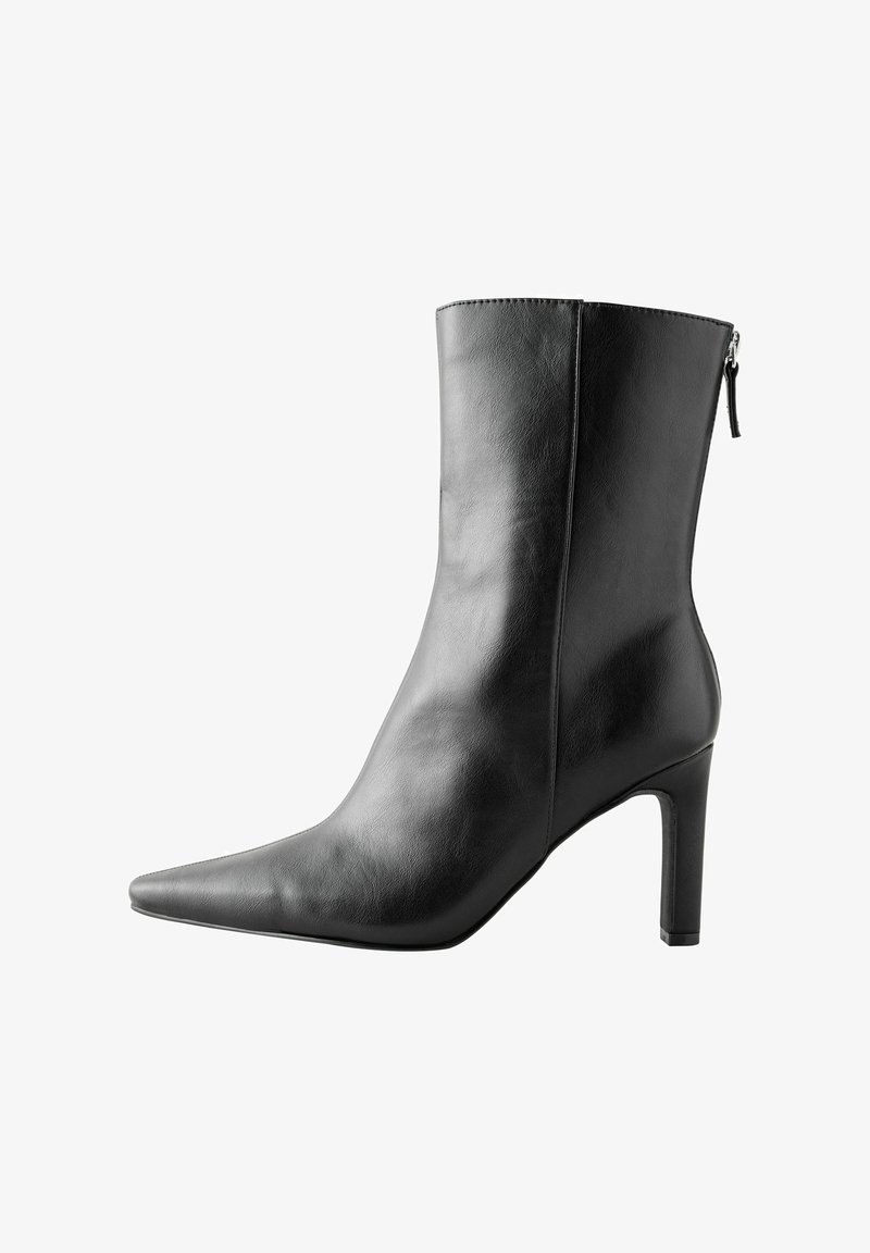 Stivale alla caviglia in pelle nera con punta appuntita, tacco alto e chiusura a zip sul retro. Texture liscia con dettagli di cucitura minimi.