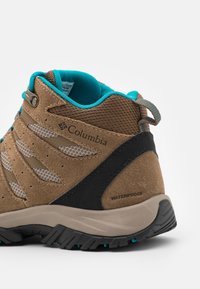 Chaussure de randonnée imperméable Columbia marron et bleu sarcelle avec semelle robuste et panneaux de ventilation en maille, vue de côté et de dos.