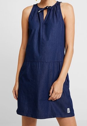 Sleeveless dark blue denim dress with a small front keyhole tied neckline and a logo near the hem on the left side.