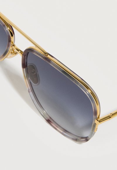 Γυαλιά ηλίου τετράγωνου σχήματος με χρυσό μεταλλικό πλαίσιο και σκουρόχρωμους φακούς με διαβάθμιση σε λευκό φόντο.