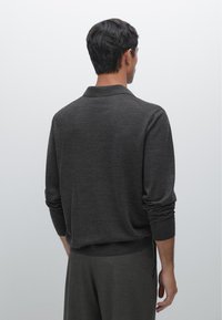 Dunkelgrauer gestrickter Polo-Pullover mit langen Ärmeln, gerippten Bündchen und einem lässigen Kragen, kombiniert mit passenden gerippten Hosen.