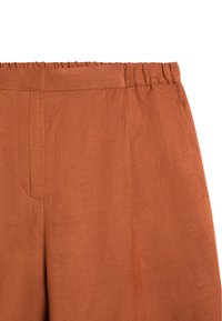 Højtaljede bukser i rustbrun med elastisk talje og subtile sømdetaljer, lavet af let, tekstureret stof.