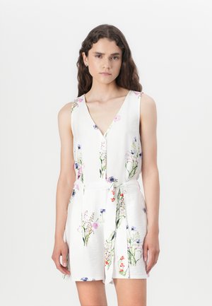 Robe combi imprimée florale en tissu blanc, avec un décolleté en V profond, un design sans manches, une ceinture adjustable à nouer, et des accents de fleurs colorées tout au long.