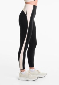 Des leggings taille haute noirs et rose clair présentent un design élégant avec un motif en color block sur le côté et une coupe ajustée pour le confort.