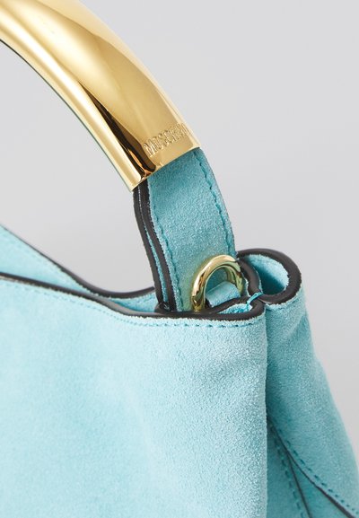 Turquoise suede handbag with a gold metal handle, featuring black trim and visible stitching details at the opening.