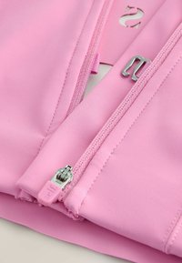 Tessuto rosa caratterizzato da un materiale liscio ed elastico. È visibile una cerniera con cursore metallico e una linguetta di plastica, con dettagli decorativi.