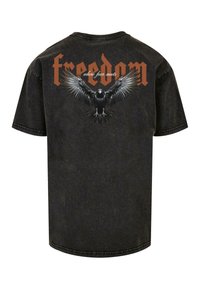 Sort bomulds T-shirt med korte ærmer, der har et stort grafik af en ørn og ordet "frihed" i orange på ryggen.