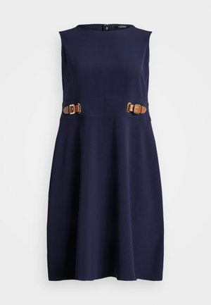 Vestido azul marino sin mangas con escote redondo, falda acampanada y dos detalles de tiras marrones con hebilla en la cintura sobre un fondo liso.