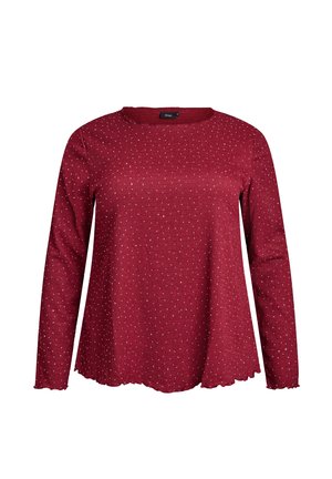 Pikad varrukad, punane pluus väikeste valgete täppidega, ümara kaelusega ning lainelike äärtega.