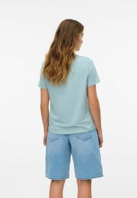  Lichtblauwe T-shirt met korte mouwen en een ronde hals, gecombineerd met lichte denim shorts met een relaxte pasvorm en zichtbare achterzakken.