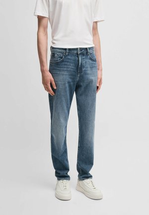 Light blue denim jeans with a straight fit, five pockets, and subtle fading. Worn with a plain white t-shirt and white sneakers.