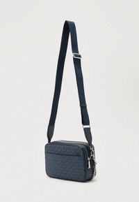 Granatowa torebka na ramię z fakturowanym wzorem, prostokątnym kształtem, zamkiem błyskawicznym, srebrnymi elementami i regulowanym paskiem. Wykonana z trwałego materiału.
