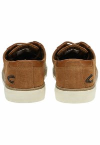 Zapatillas de ante marrón con suelas de goma blanca. Presentan un detalle de costura y un pequeño logo negro en el talón. Los cordones están atados por dentro.