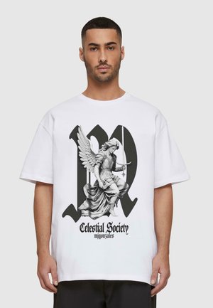 Hvid oversized T-shirt med et sort og gråt grafisk motiv af en engel med vinger, som holder et sværd og bærer flagrende klæder. Teksten nedenfor lyder "Celestial Society."