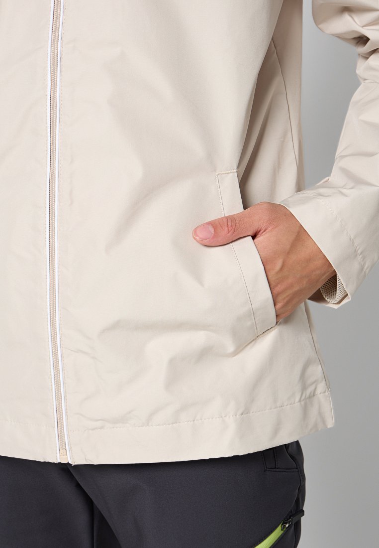 Chaqueta ligera beige con cremallera frontal, dos bolsillos laterales y un tejido suave y resistente al agua. Presenta un corte holgado y líneas limpias.