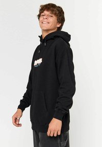 Hoodie noir avec une poche avant, capuche à cordon réglable et un design graphique coloré sur la poitrine. Matière douce et texturée.