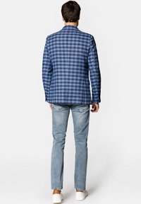 Niebieska marynarka w kratę wykonana z tkaniny tkanej, zestawiona z jasnoniebieskimi dżinsami. Marynarka ma klapę o wycięciu oraz strukturalny krój.