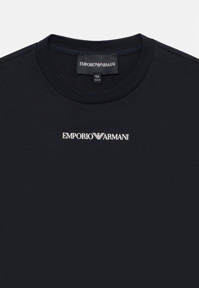 Schwarzes Baumwoll-T-Shirt mit Rundhalsausschnitt, kurzen Ärmeln und einem weißen Aufdruck des "Emporio Armani" Logos auf der Vorderseite. Glatte Textur.