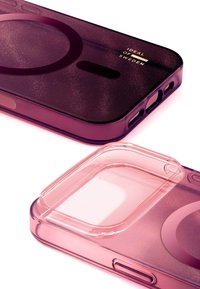 Telefondeksel med magentafarget gradient, glatt finish og sirkulær aksent. Har utsparinger til knapper og kamera. Jevn, teksturert overflate.