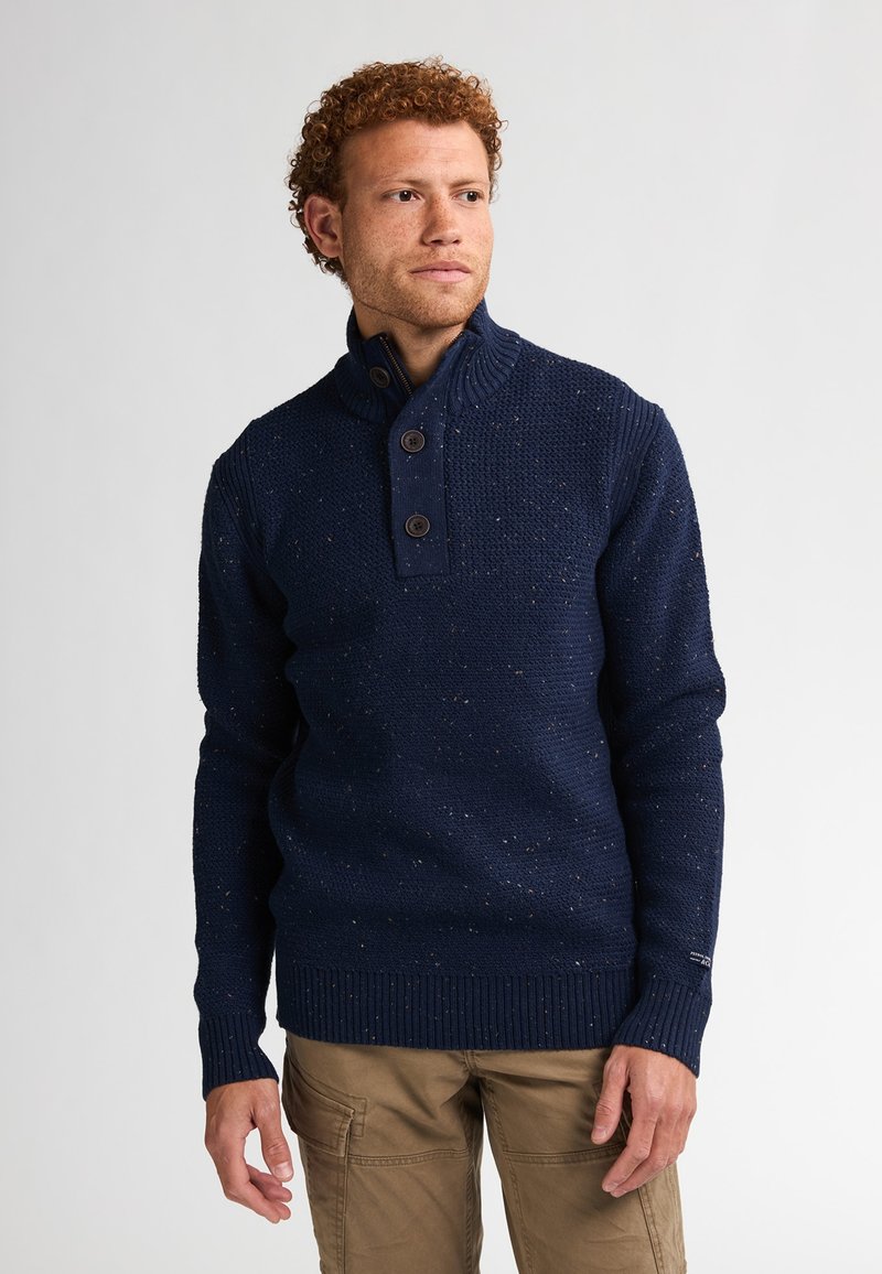 Pull en tricot bleu marine avec un col haut, deux boutons foncés et un motif texturé, avec des poignets et un ourlet côtelés.