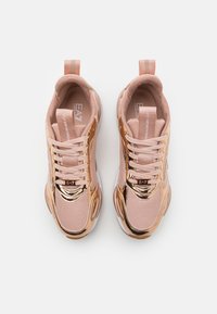 Athletic sneakers in light pink mesh with rose gold metallic accents and white sole. Features laces and a pull tab at the heel.