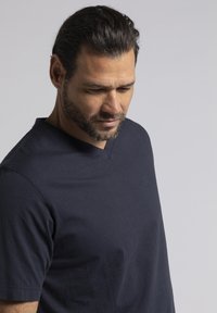 Camiseta navy de cuello en V hecha de suave algodón, con mangas cortas y un logotipo sutil en el pecho, con una textura lisa y sencilla.