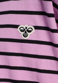 Lila- och svartrandig tyg har en vit broderad bi-logotyp placerad på vänster sida. Texturen verkar mjuk och stickad.